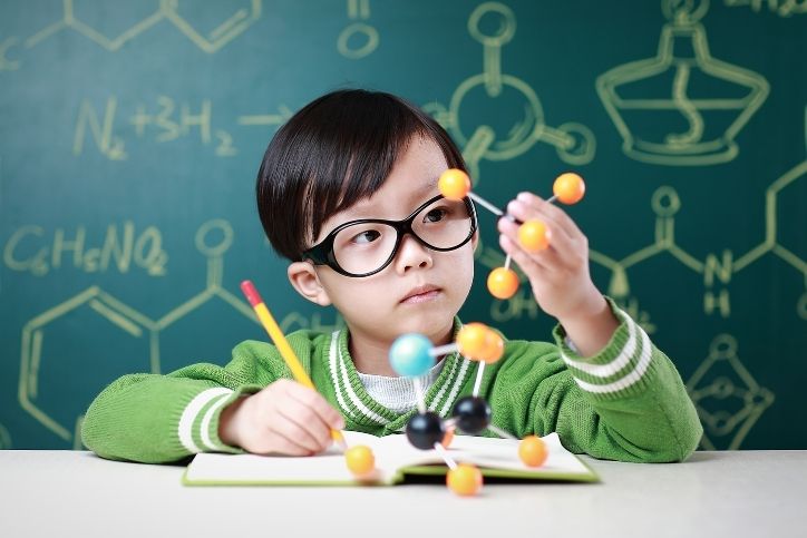 menino explorando modelo molecular em aula de ciências.